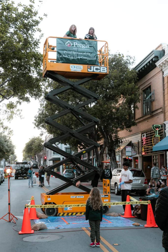 Child looking up at two women on a scissor lift