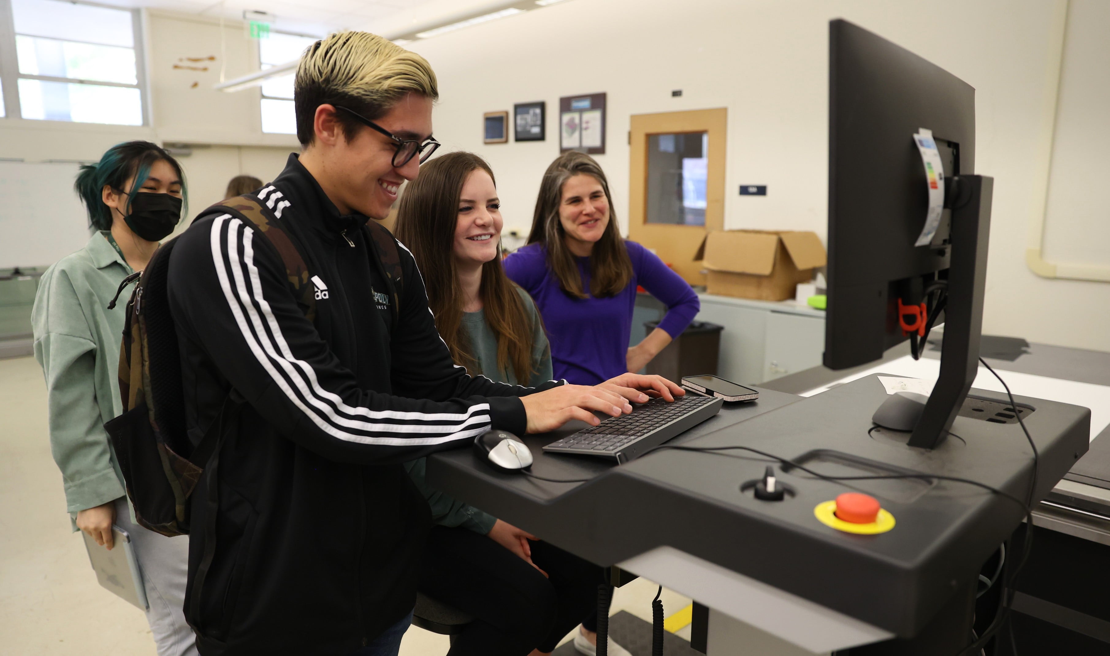 Students work on a graphic design computer and printer in a lab