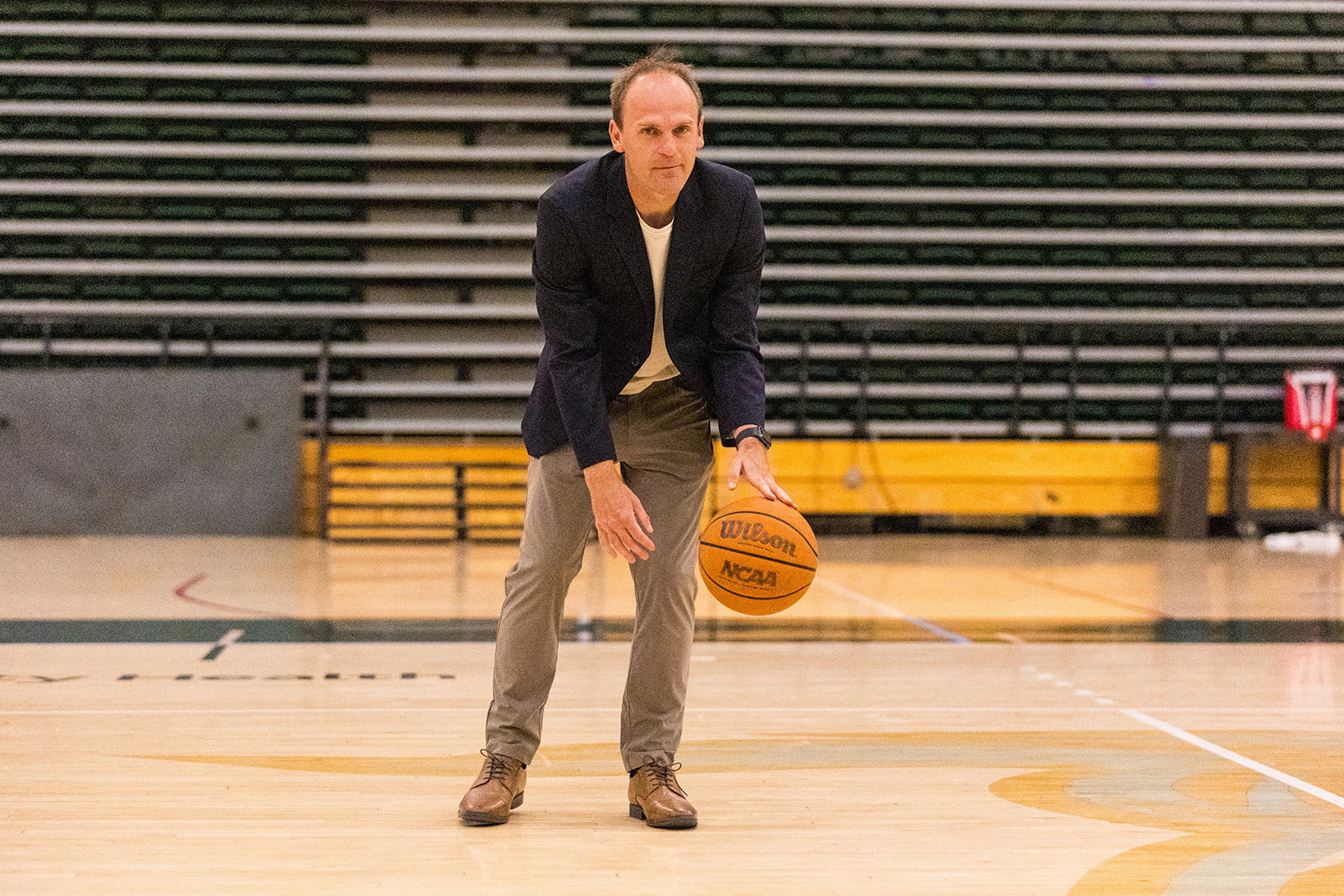 Professor Joseph Kuehn dribbles a basketball on the court