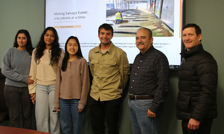 A group of students, their faculty adviser, and a project sponsor stand in front of the JackRabbit website they helped refine