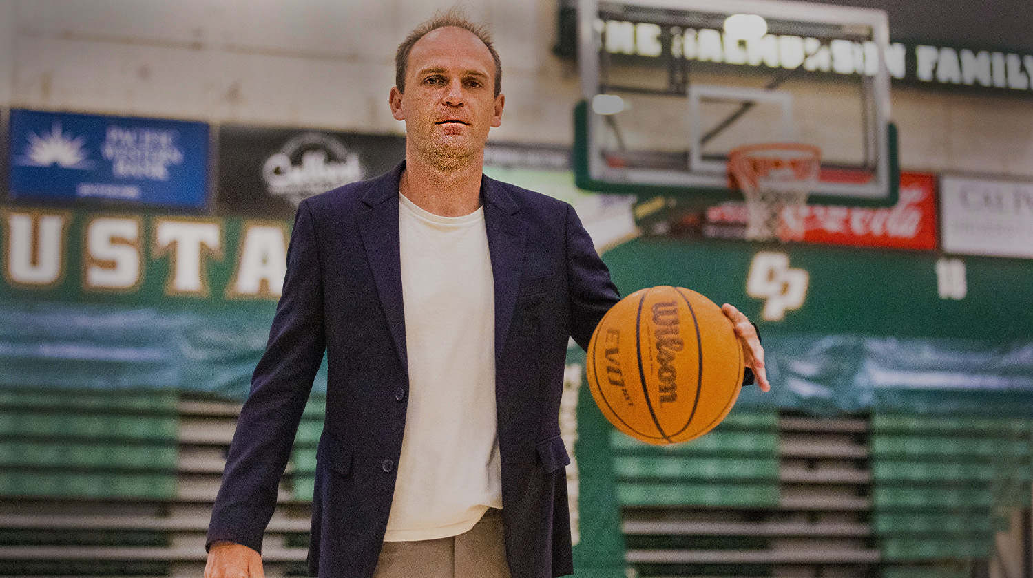 A professor dribbles a basketball on the Cal Poly basketball court