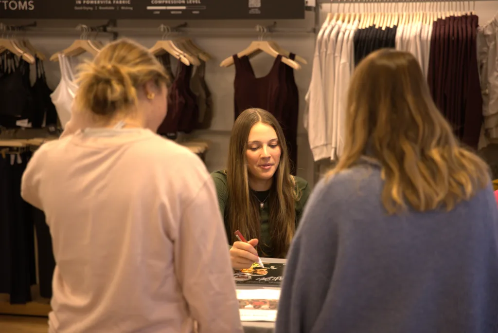 A member of the Cal Poly volleyball team signs autographs at a store