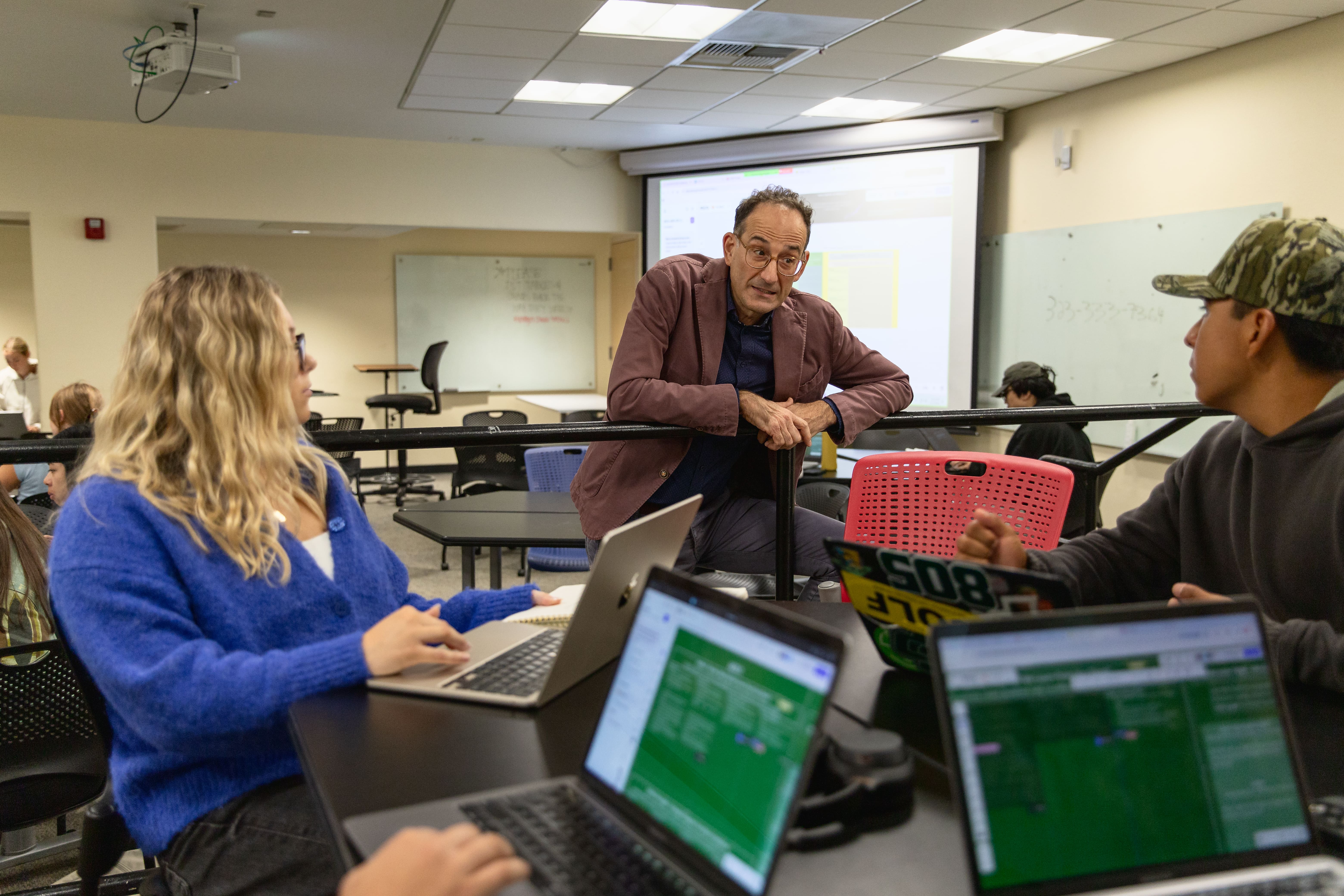 Stern Neill, center, speaks to students Kate Denger, left, and Daniel Altamirano during his Marketing Strategy course, which has extensively used AI. (Photo: Jahan Ramezani)