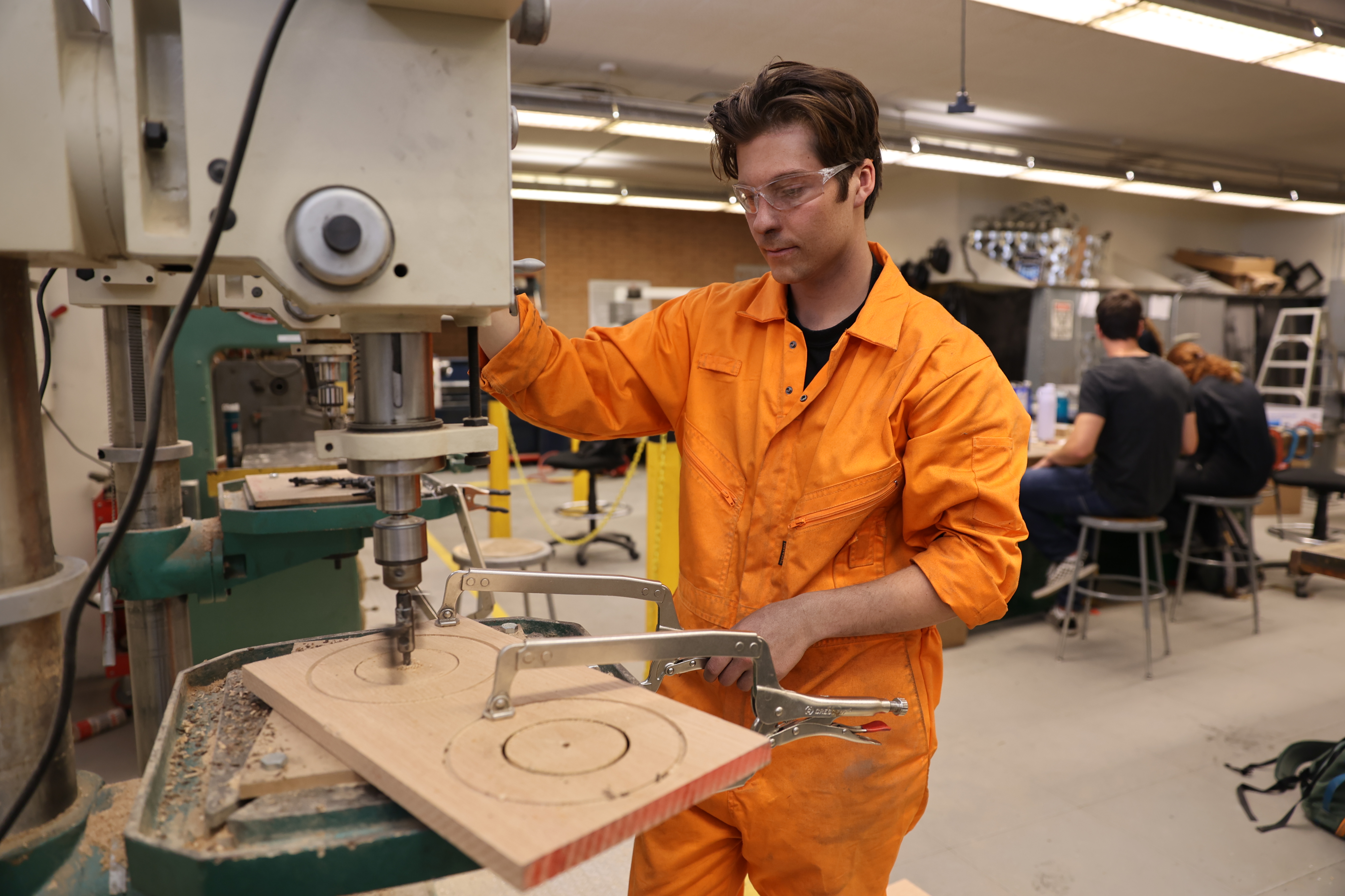 A student works on a ,machine in an industrial tech lab.