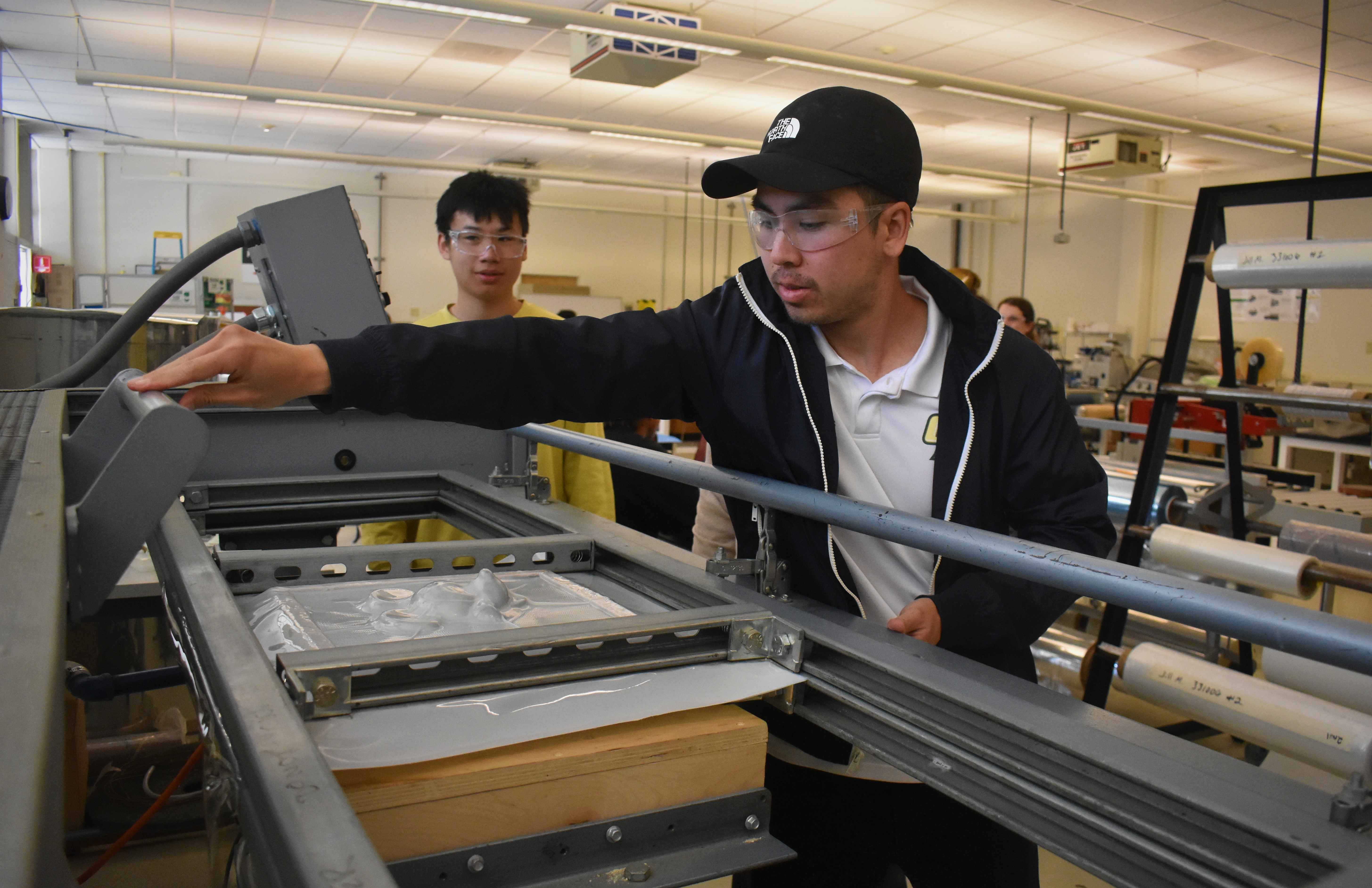 A packaging student uses a machine to produce a product