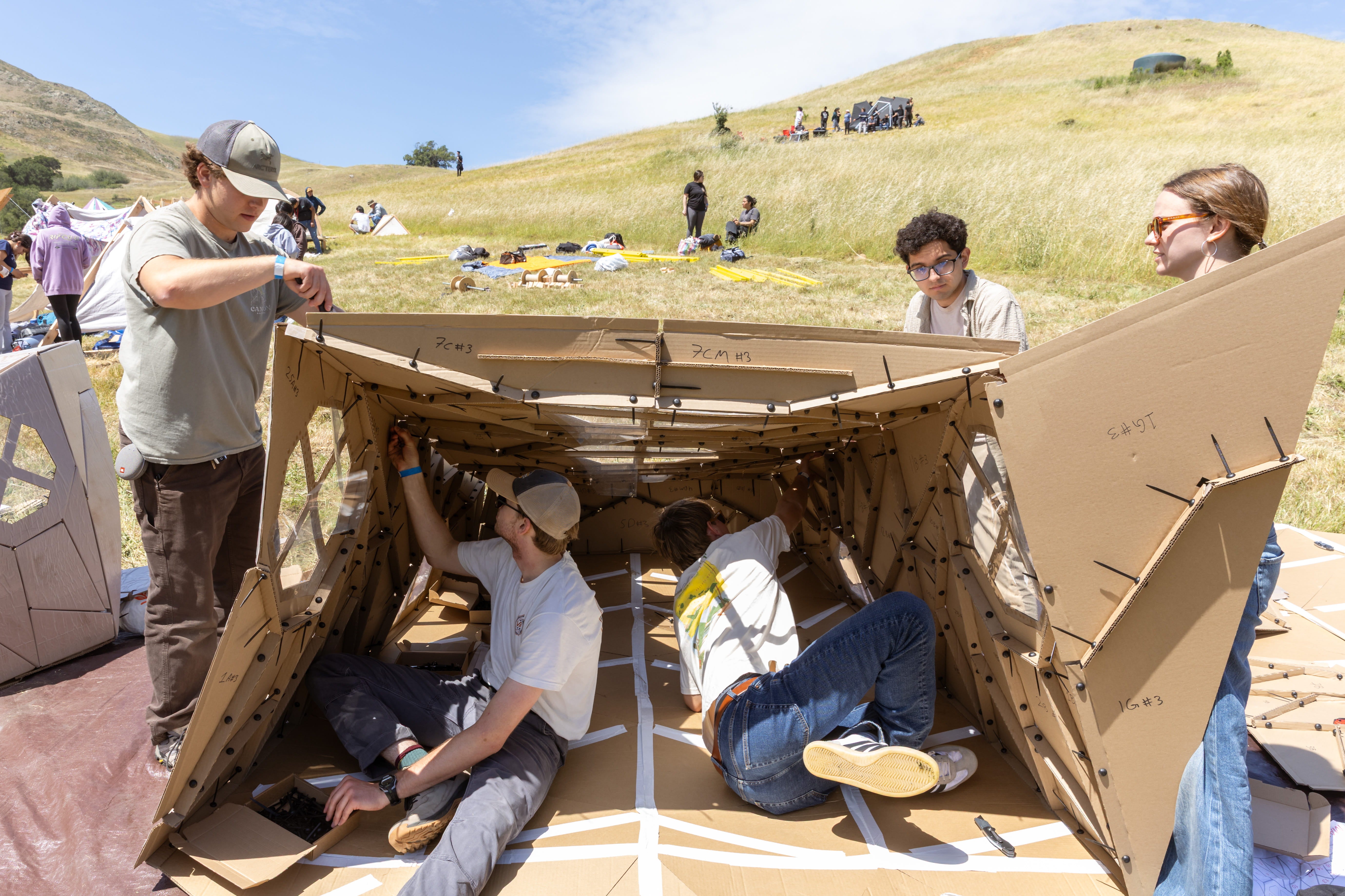 Students in the packaging program work on their cardboard shelter in the Design Village
