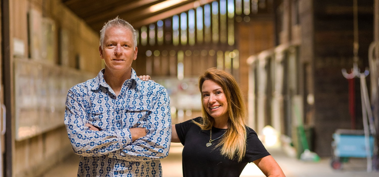 Simon and Caprice Arkell pose for a portrait inside a horse barn