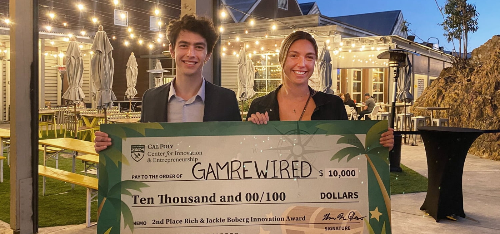 Two startup entrepreneurs hold up an enlarged check after a contest win