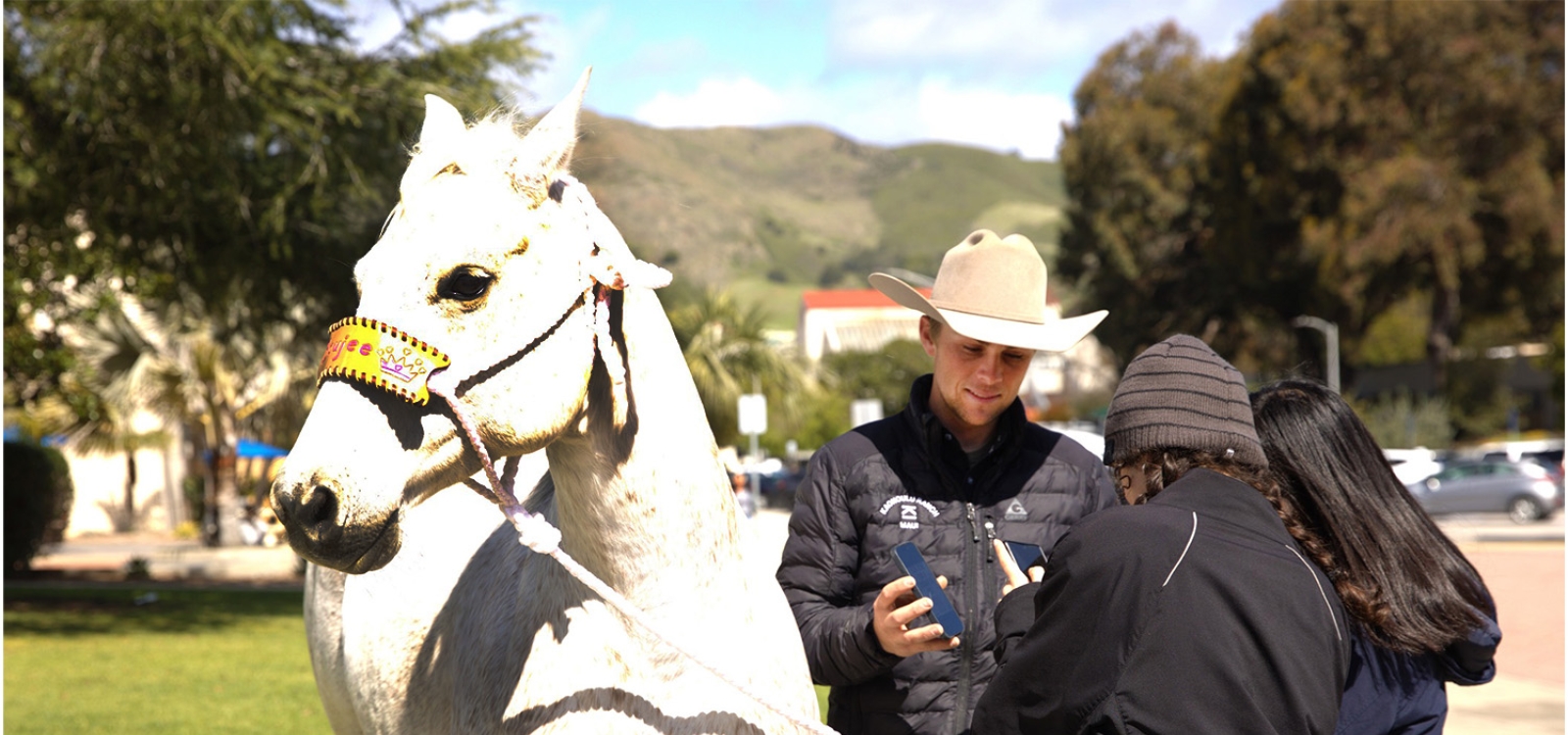A rodeo athlete talks with students as he stands next to his horse