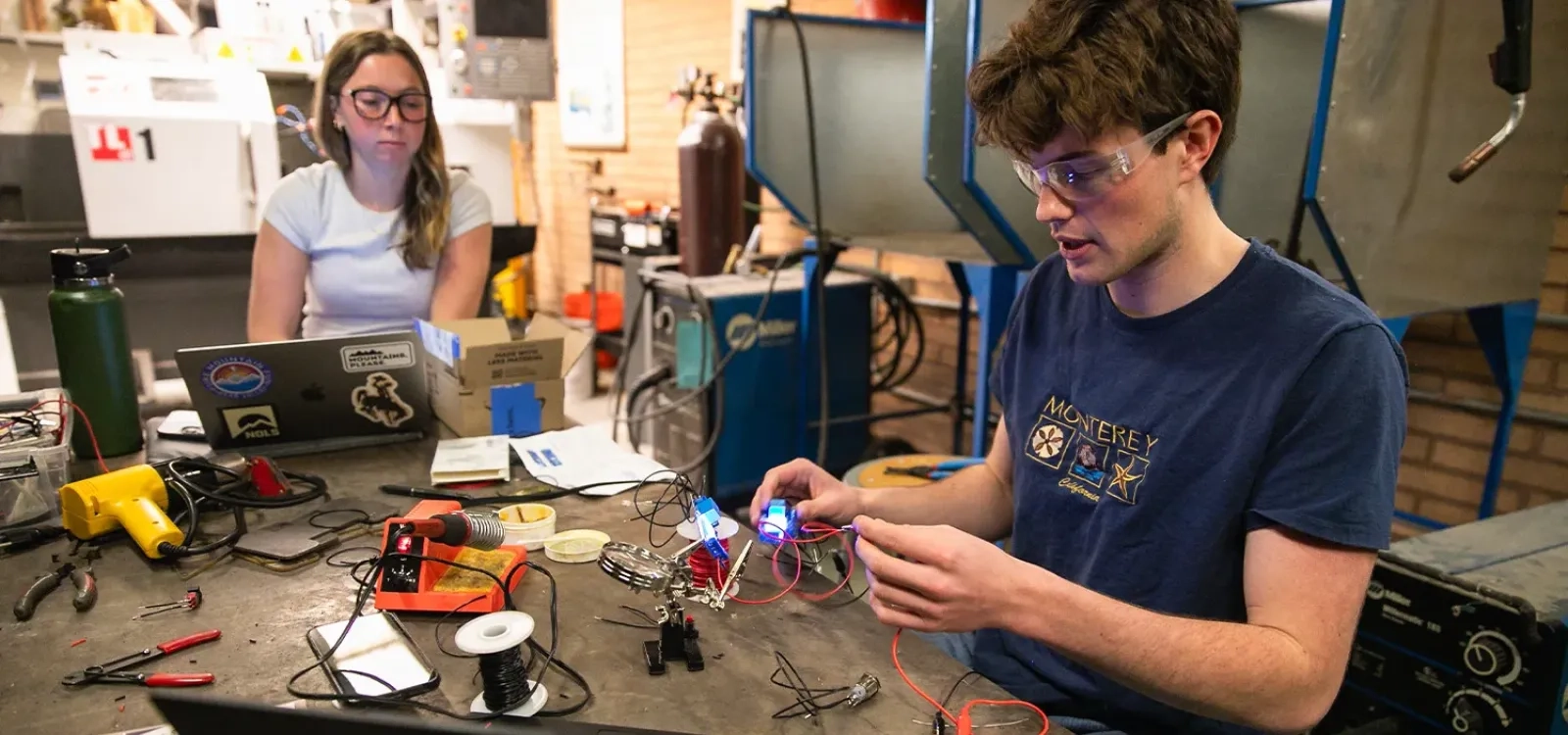 Two students work on a project that involves wires in a lab