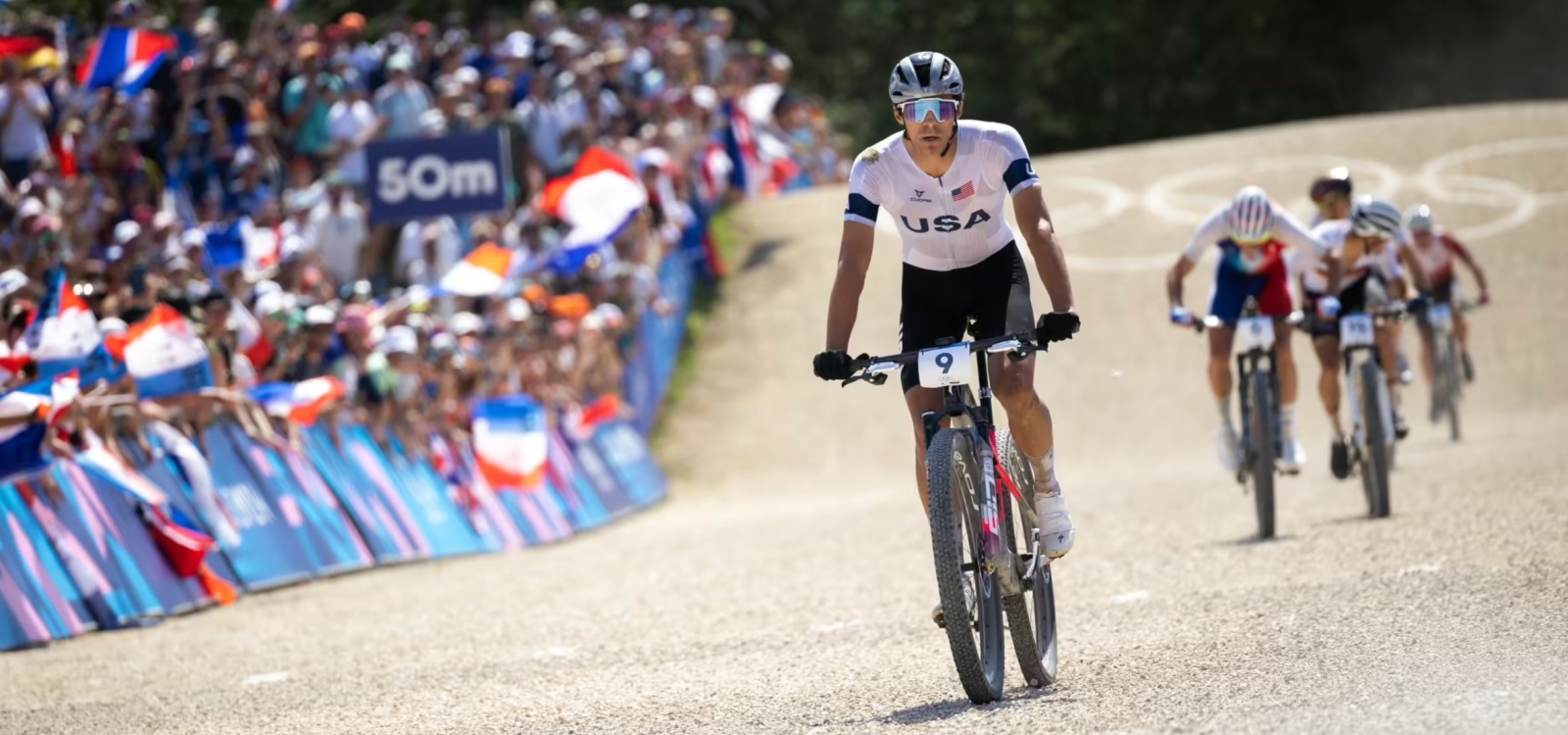 Christopher Blevins races his bike on pavement with a crowd watching