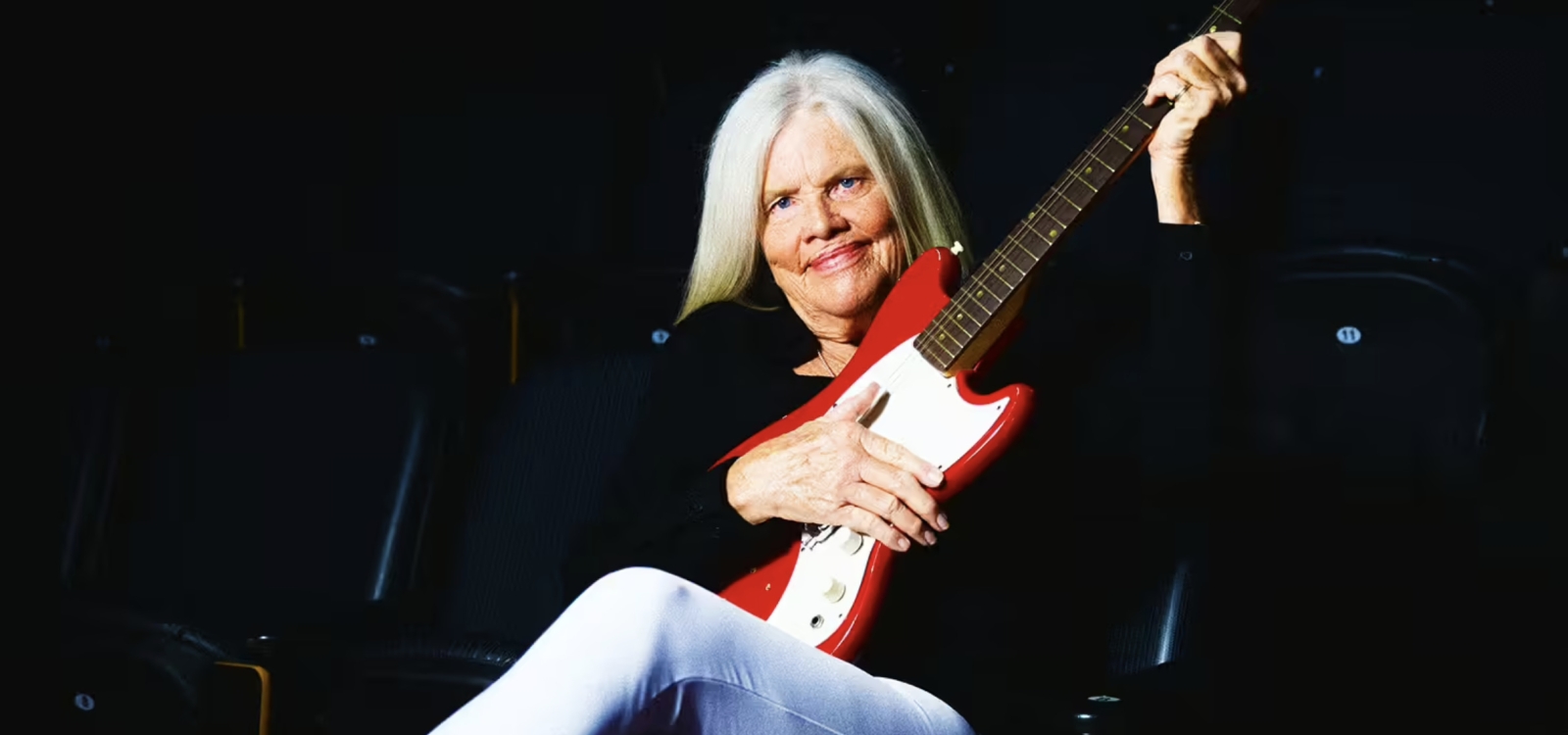 Colleen Duffy-Smith, sitting with an electric guitar in her hands
