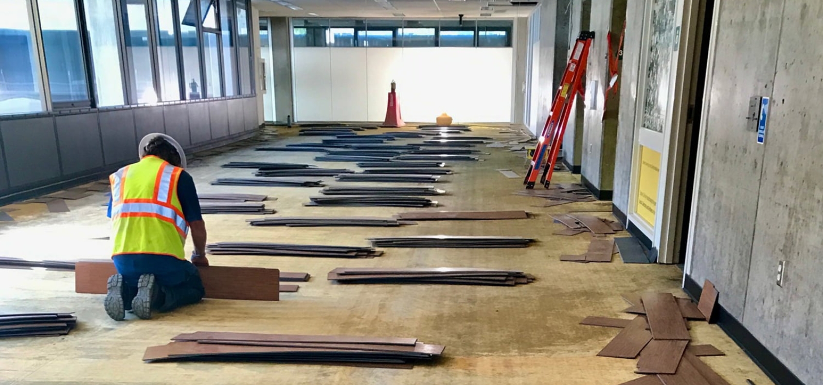 Construction worker carefully pulling up flooring from Kennedy Library during its transformation