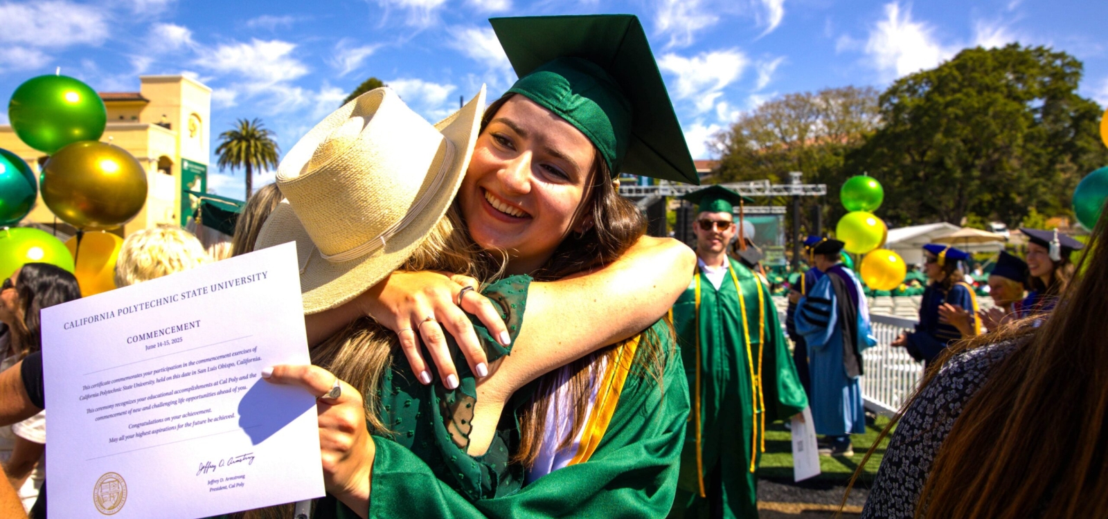 Graduate holding her diploma hugging someone