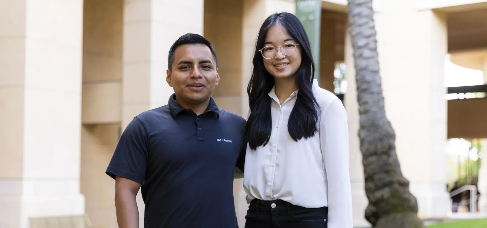 Two students pose outside the business building