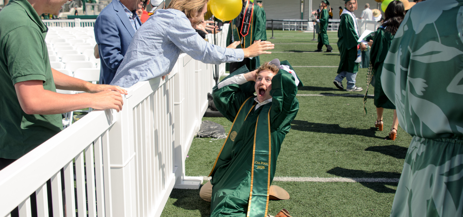 A graduating student falls to his knees in jubilation