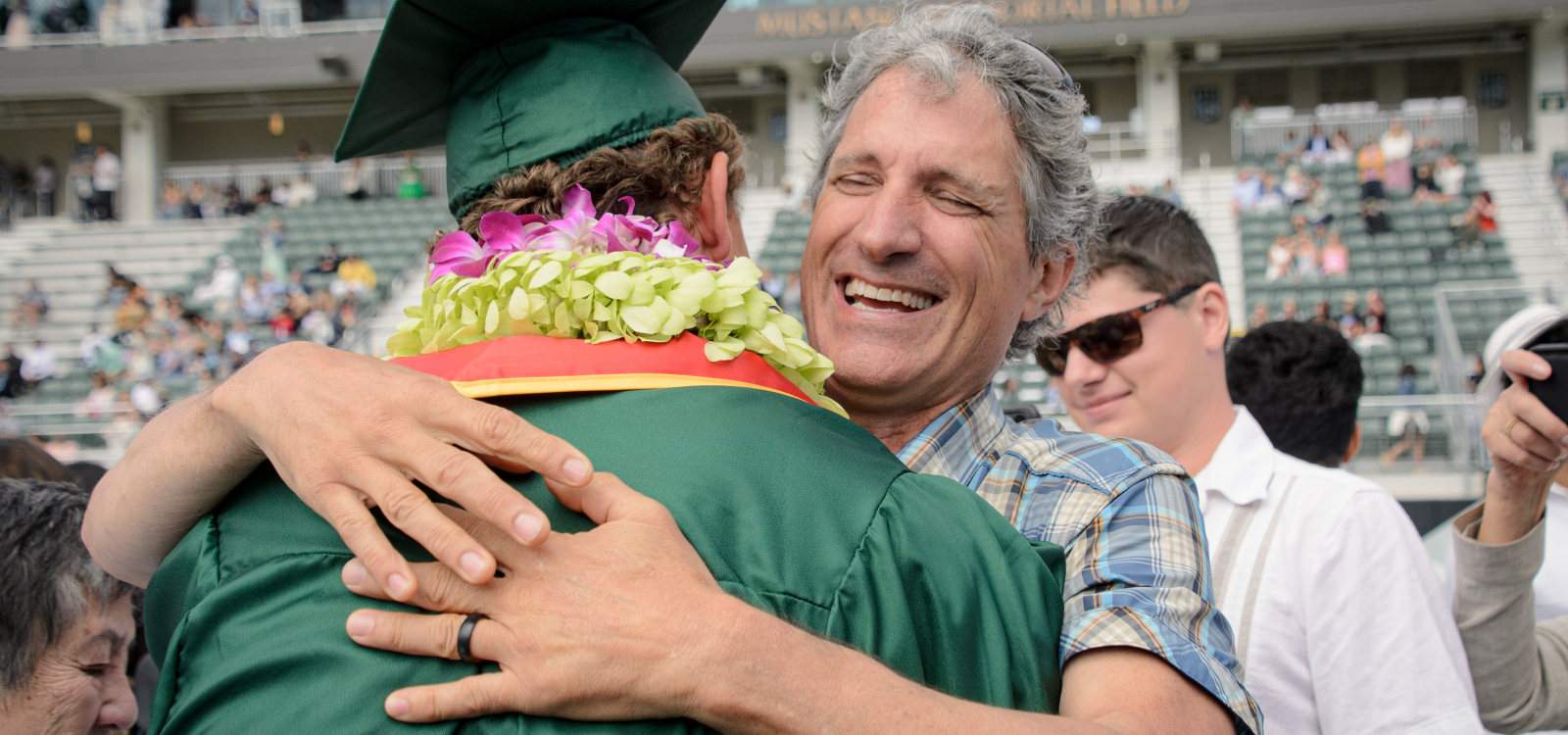 A father hugs his graduating son at commencement