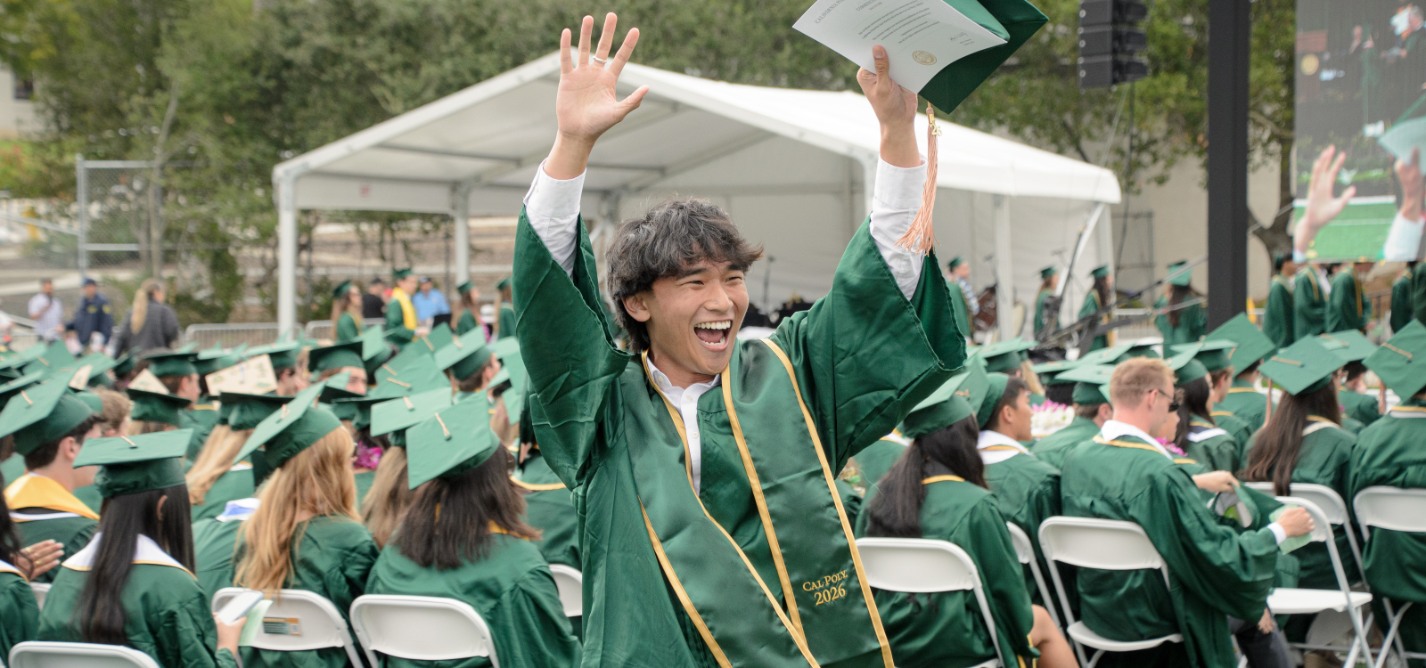 A graduating student raises his hands in celebration