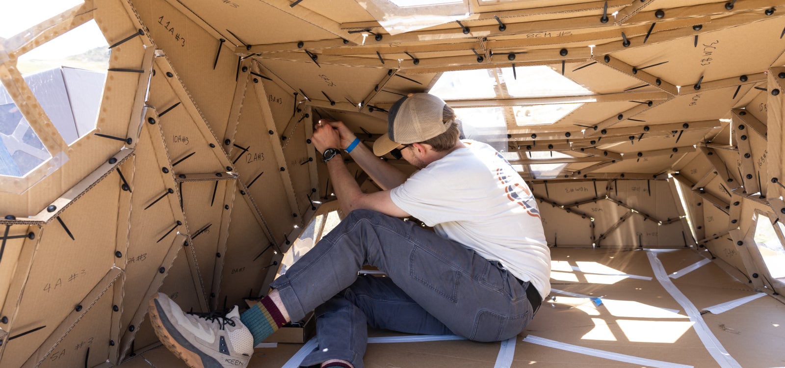 A student works inside the corrugated shelter.