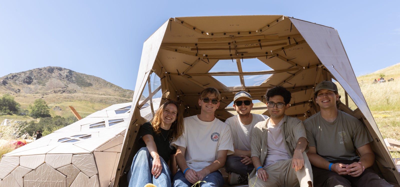 Students sit inside the corrugated shelter
