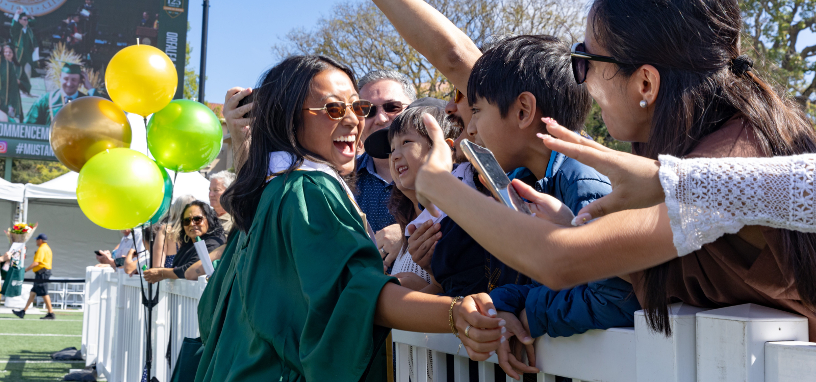 A new grad gets celebratory hugs from family and friends