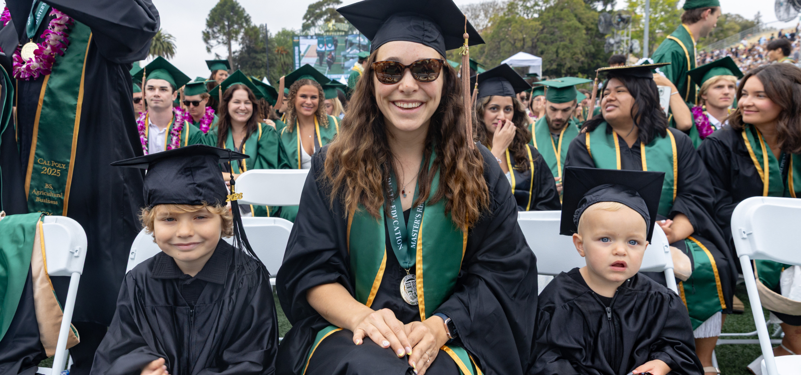 A graduating master's student sits with two young children
