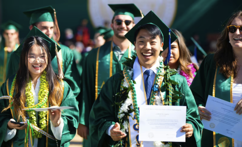 Group of happy students at commencement showing their diplomas