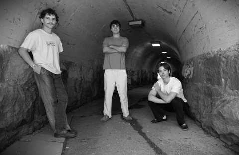 Three students pose for a portrait in a tunnel