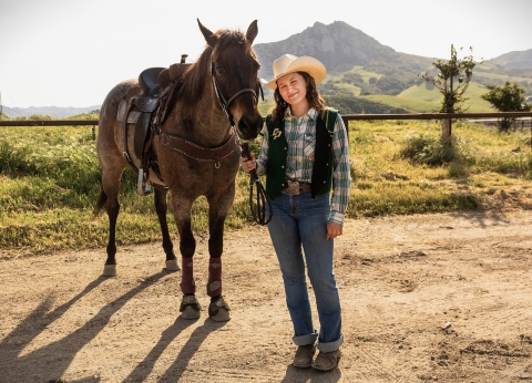 Layla Hanna and her horse, standing on a dirt road in the hills surrounding Cal Poly