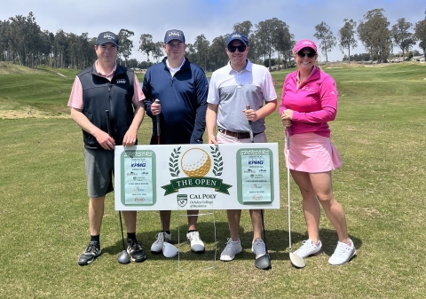 Group of golfers pose for photo behind fundraising sign