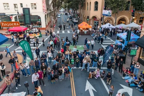 People stand in the street looking up at the scissor lift where the egg will be dropped from