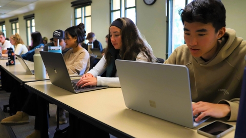 Students in a classroom working on their laptops.