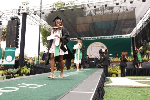 Kim Bhunu, in cap and gown and diploma in her hand, at commencement