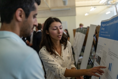 A student discusses her research next to a poster