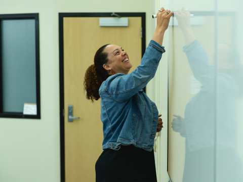 Erica A Stewart writes on a whiteboard during a class.