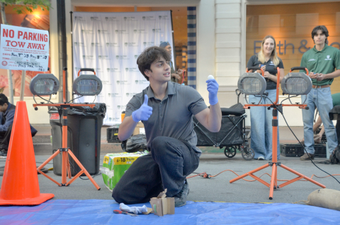 A packaging student holds up an intact egg and offers a thumb's up