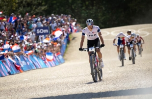 Christopher Blevins races his bike on pavement with a crowd watching
