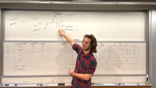 Jack Jeefer pointing to an equation on a white board in front of a class