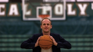 A professor poses with a basketball on a court