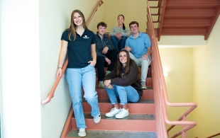 Members of the Forge Capital Group sitting on stairs in a stairwell