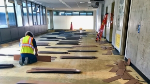 Construction worker carefully pulling up flooring from Kennedy Library during its transformation