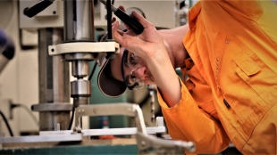 Student operating machinery to create a lighting prototype.
