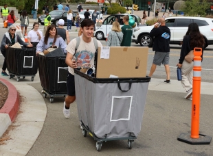 Students pushing cards full of belongings returning to campus after summer break