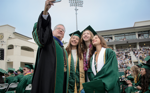 A trio of students pose for a selfie with Cal Poly President Jeffrey D. Armstrong