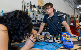 Miles Clarke watches a student perform work in the EMPOWER lab