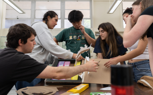 A team of packaging and graphic design students work on a project in a lab