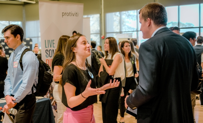 Female student speaking to male representative at job fair