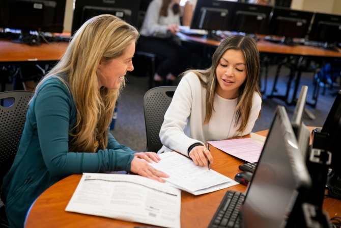 Female professor reviewing documents with student