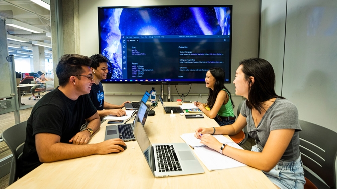 Students working on laptops and viewing on tv