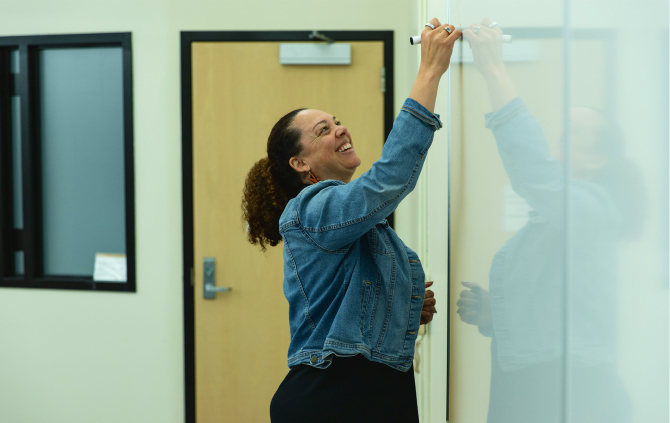 Erica A Stewart writes on a whiteboard during a class.